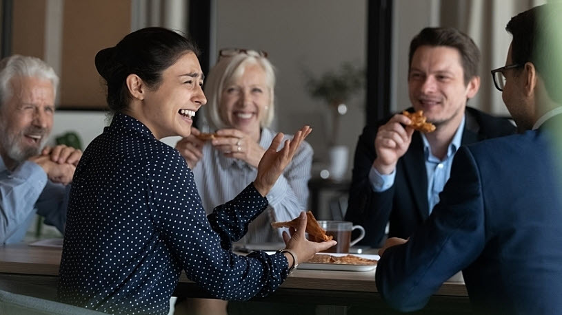 happy diverse employee group eating pizza in office