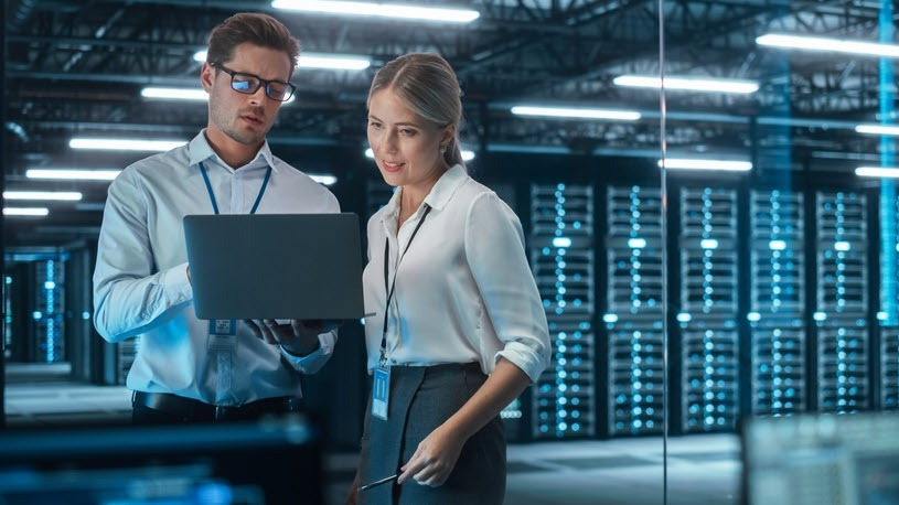 Female and male data engineers work in server room