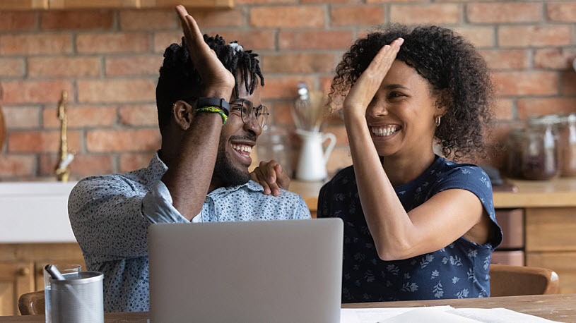 Black couple celebrating financial success at laptop Black couple celebrating financial success at laptop