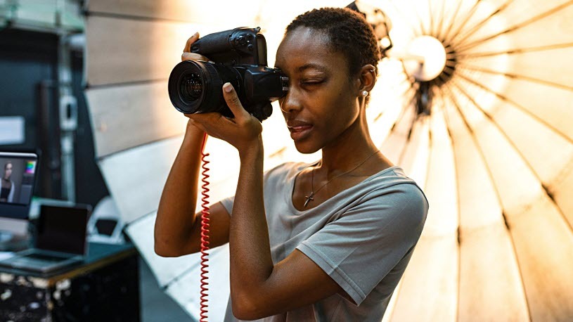 Image of a young photographer in studio with light kit behind her Image of a young photographer in studio with light kit behind her