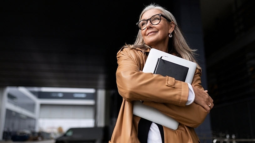 Mature businesswoman with laptop and journal in hands smiling Mature businesswoman with laptop and journal in hands smiling