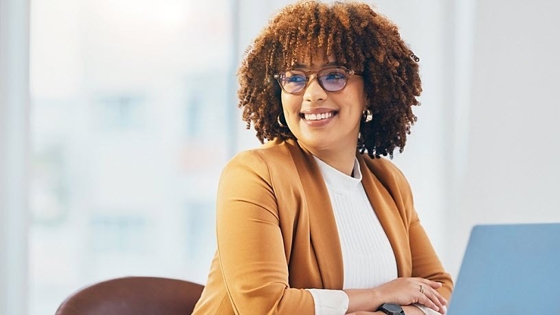 Black women at office with glasses on face smiles looking away Black women at office with glasses on face smiles looking away