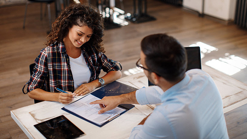 Young woman signing contract with HR manager