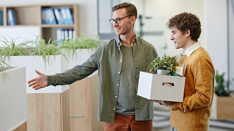 photo of young male employee being shown his desk by manager photo of young male employee being shown his desk by manager