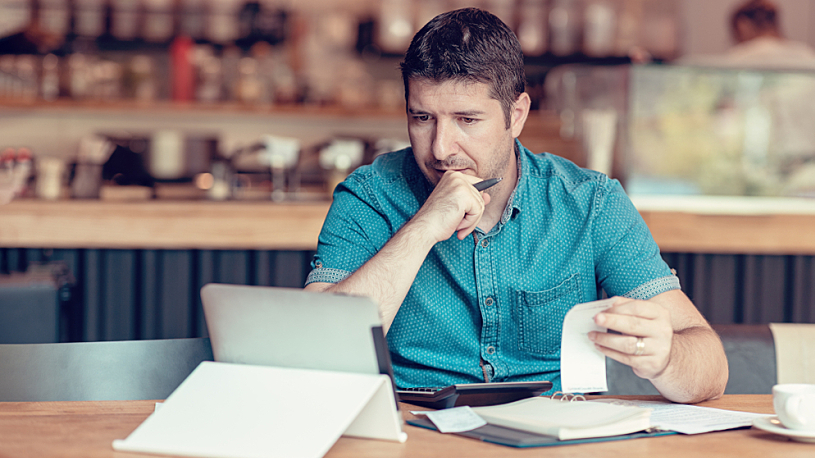 Filing Back Taxes A businessperson sits handling papers at a kitchen table.