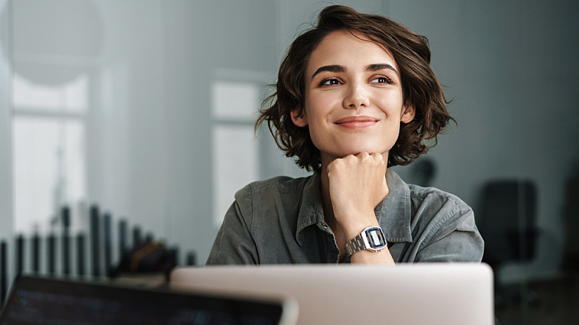 A businesswoman smiles while sitting at her laptop.