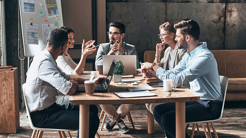 Employee Strengths Coworkers work together at a conference room table.