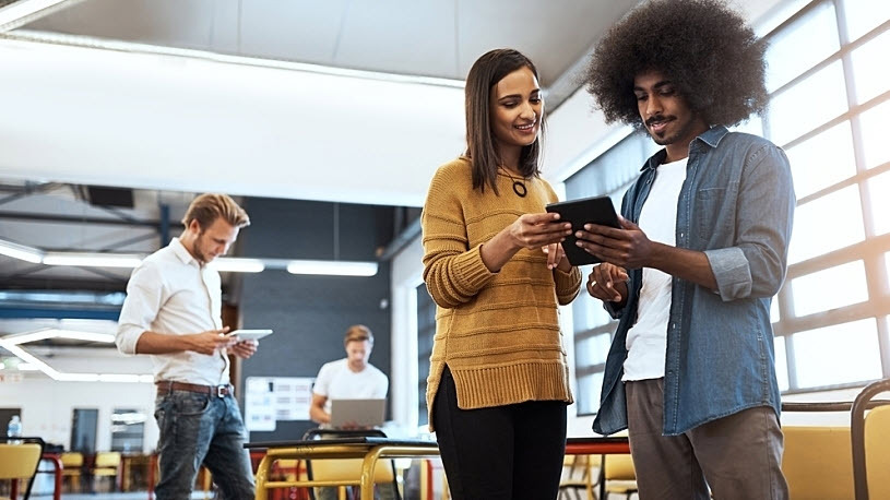 two young employees comparing notes on a computer tablet