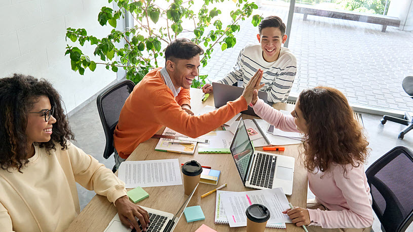 Gen Z Employees Four young professionals work together with laptops while seated at a conference table.