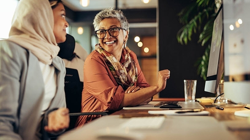 Two happy businesswomen chatting while working Two happy businesswomen chatting while working