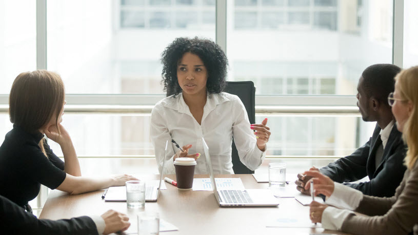 Generative AI A woman leads a meeting at a conference table in an office.