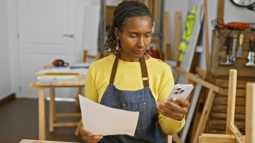 African American woman reads document and uses smartphone African American woman reads document and uses smartphone
