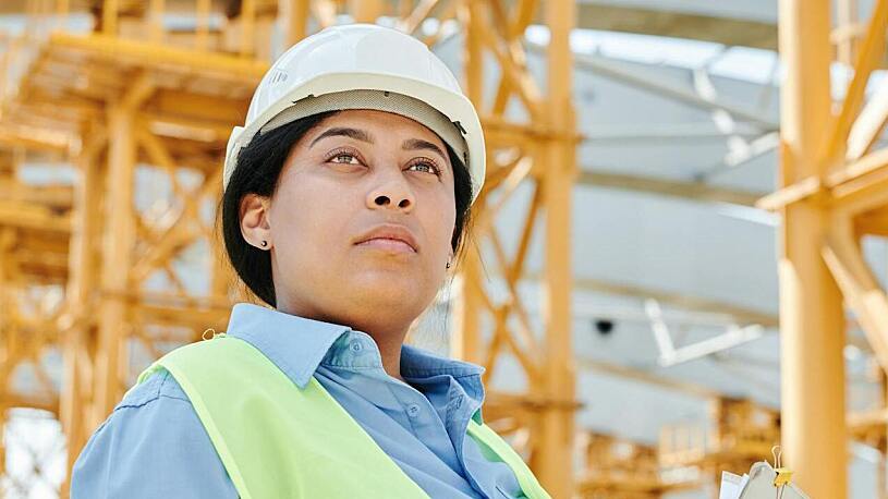 Construction Talent Pool A woman wearing a hard hat and safety vest on a job site.