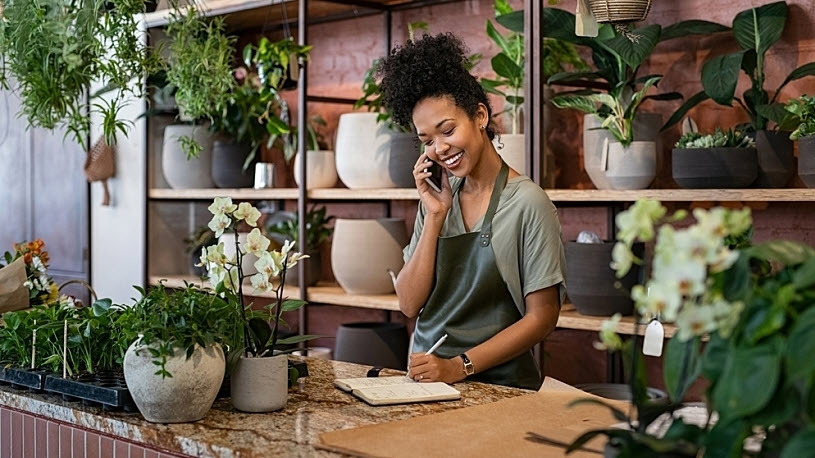Smiling woman business owner in her botanical shop on phone Smiling woman business owner in her botanical shop on phone