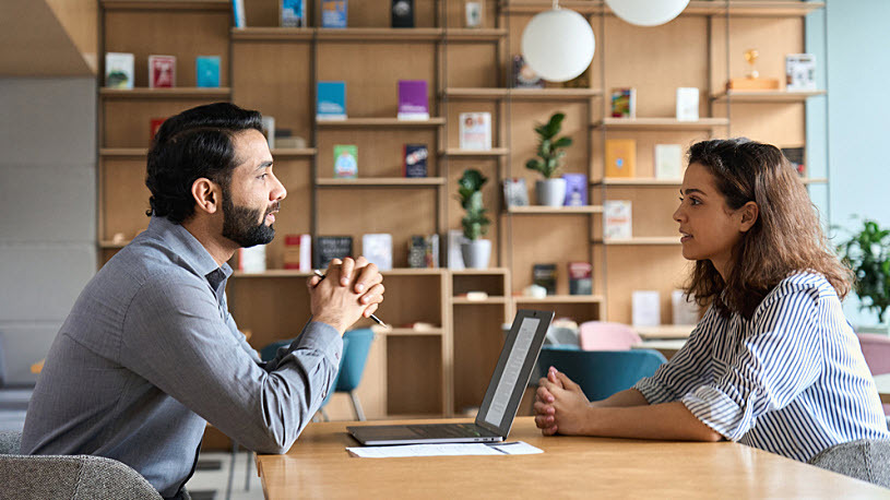 How HR Leaders Can Succeed in 2025 An HR leader sits at a desk while meeting with an employee in an office.