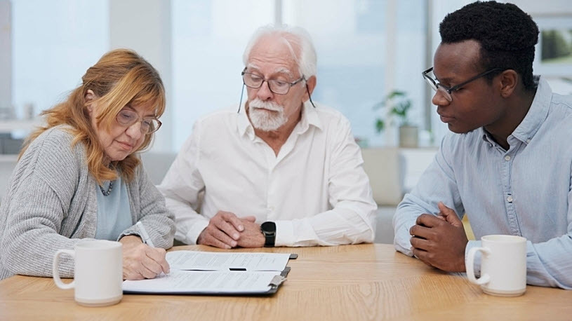 Retirement-aged couple meeting at table with financial advisor Retirement-aged couple meeting at table with financial advisor