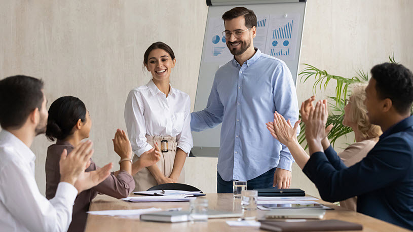 Smiling male leader announces employee awards in meeting Smiling male leader announces employee awards in meeting