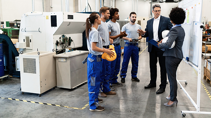 5 Advantages of Benefits Administration Outsourcing Manager in suit talking to diverse group of industrial employees