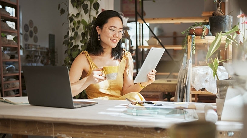How to Do Payroll for Small Business A woman sits at her small business office desk smiling looking at document