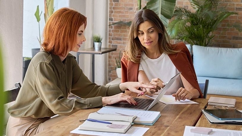 two busy professional women working together at office table two busy professional women working together at office table