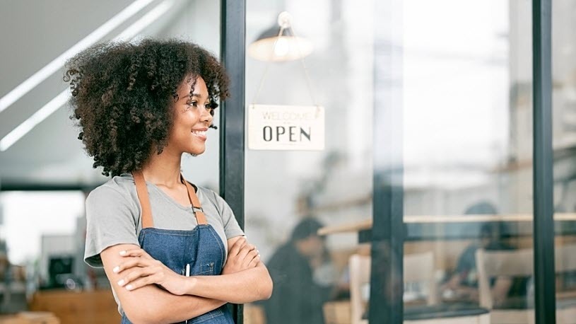 smiling female coffee shop owner looks happy at entrance smiling female coffee shop owner looks happy at entrance with open sign behind her