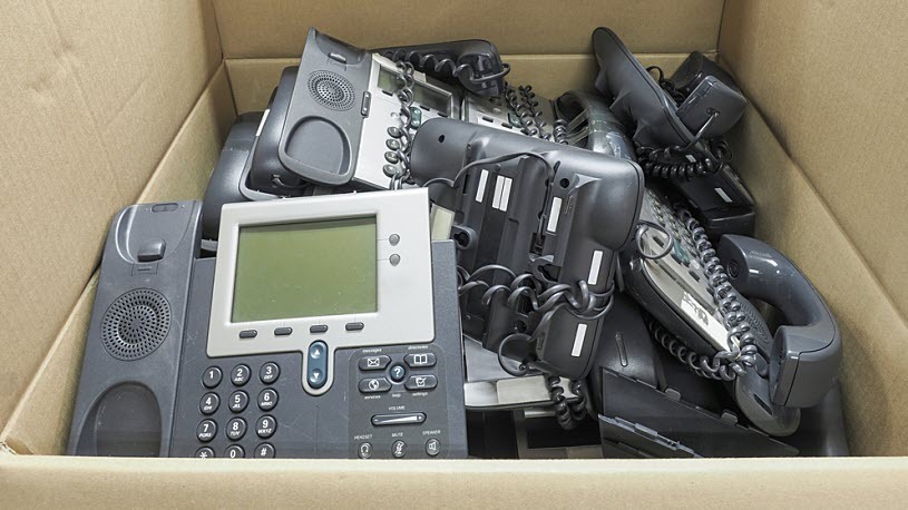 A box of retired office telephones ready for recycling A box of retired office telephones ready for recycling