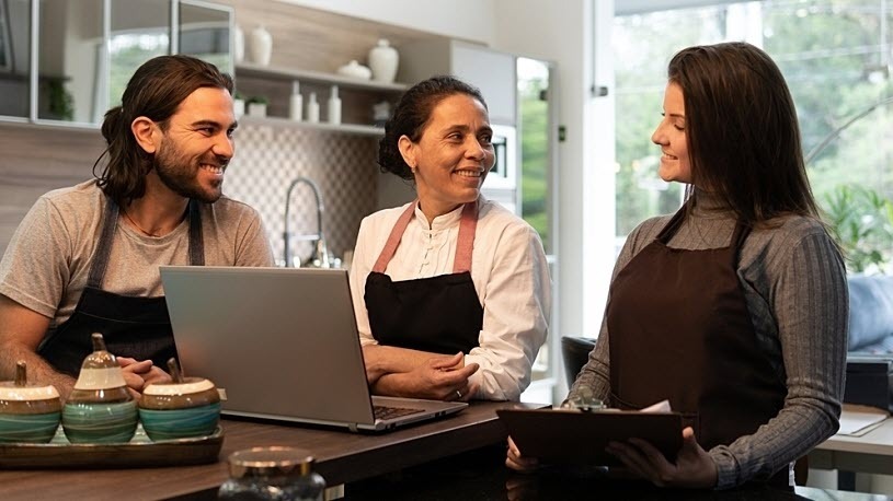 Three small business co-workers smile in conversation inside shop Deciding Wiser: Is an ICHRA Health Plan Right for Your Business Model?