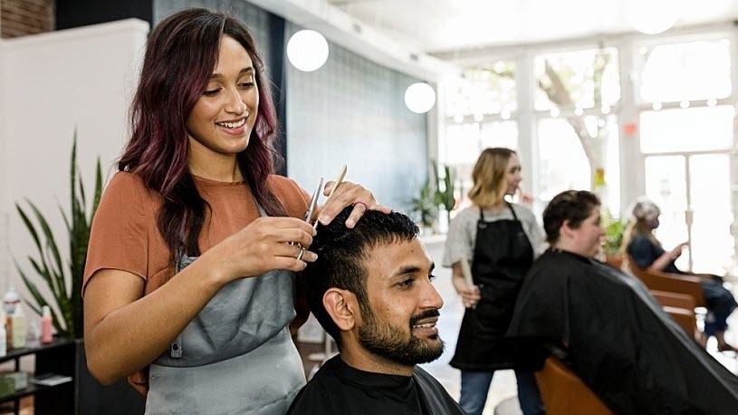 Man getting haircut from a smiling hair stylist at a barber shop Man getting haircut from a smiling hair stylist at a barber shop