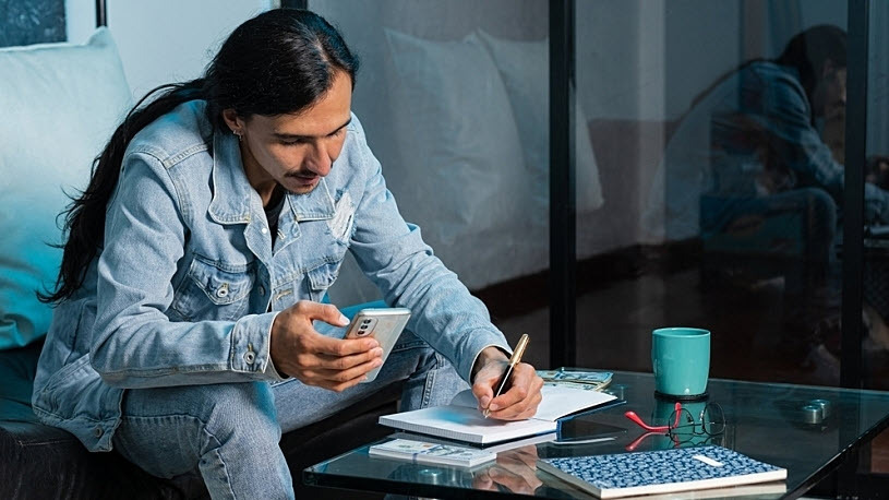 An employee at home using his phone to review his finances An employee at home using his phone to review his finances