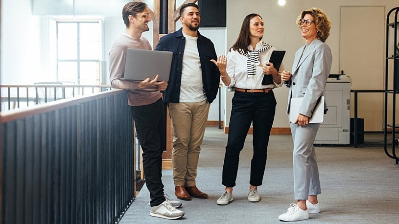 Smiling manager meets with diverse team in office hallway Smiling manager meets with diverse team in office hallway
