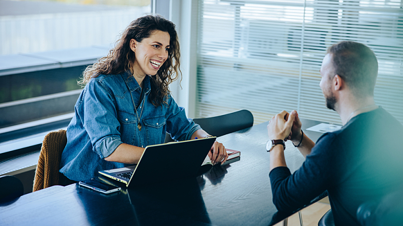 Rehiring Former Employees Can Be Advantageous smiling businesswoman taking interview of job applicant at office desk