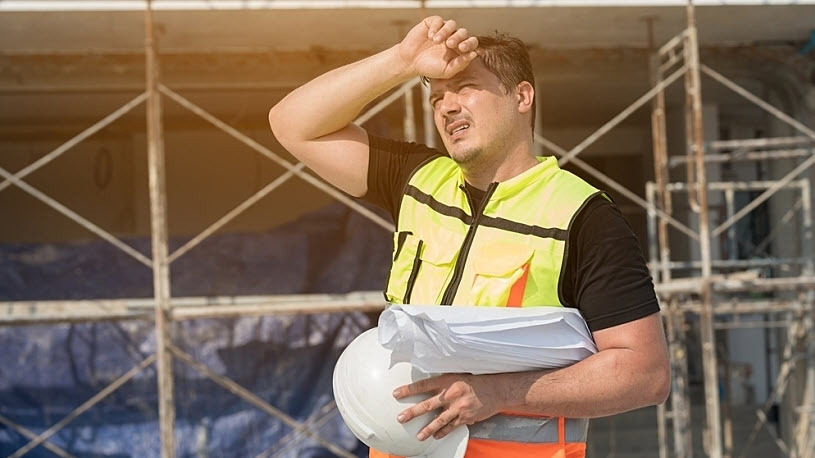 Male construction engineer wipes brow working outside in the sun Male construction engineer wipes brow working outside in the sun