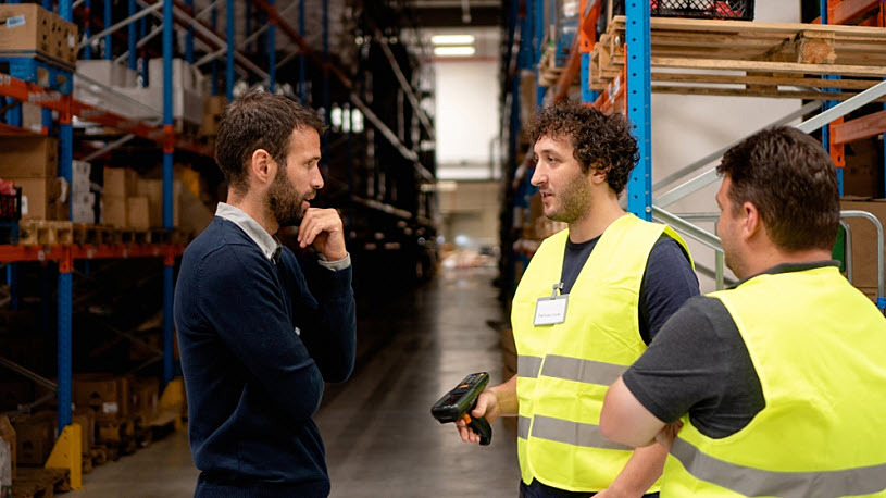 The manager talks to two warehouse workers The manager talks to two warehouse workers