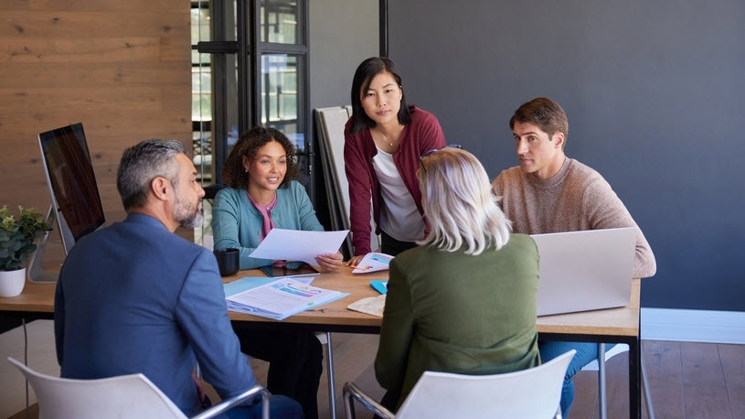 Workforce planning collaboration Five people at a table with laptops