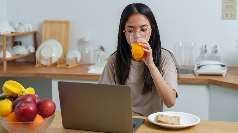 Young woman drinks juice and eats breakfast while working at home Young woman drinks juice and eats breakfast while working at home