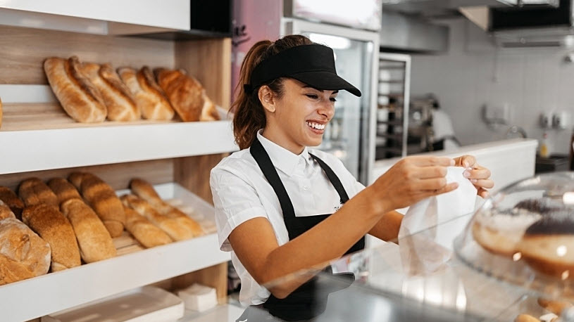 Bakery worker bags up bread for customer at counter Bakery worker bags up bread for customer at counter