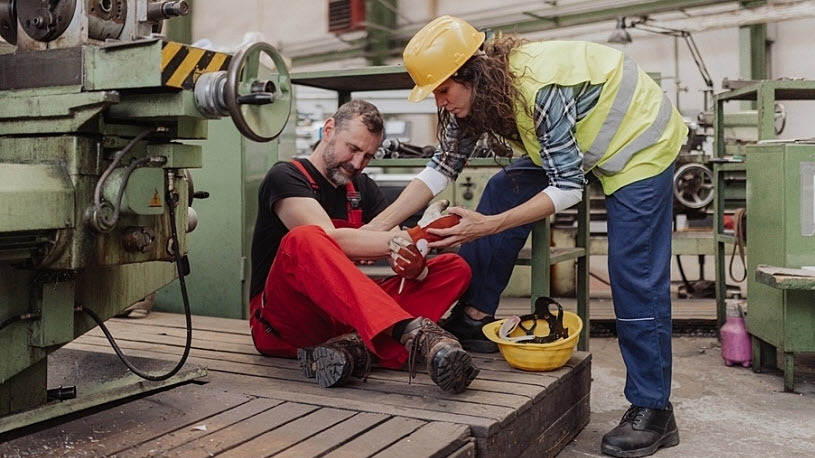 Woman is helping her colleague after workers' compensation injury Woman is helping her colleague after accident in factory. First aid support on workplace