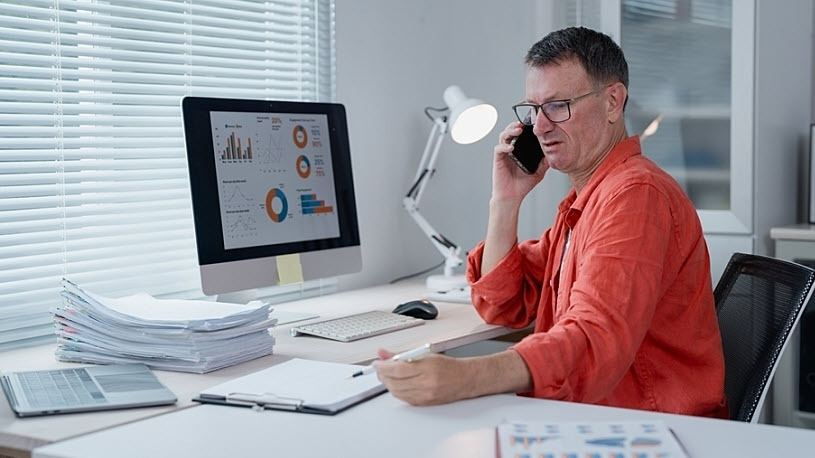 Businessman is talking on his phone reviewing financial charts Businessman is talking on his smartphone and reviewing financial charts