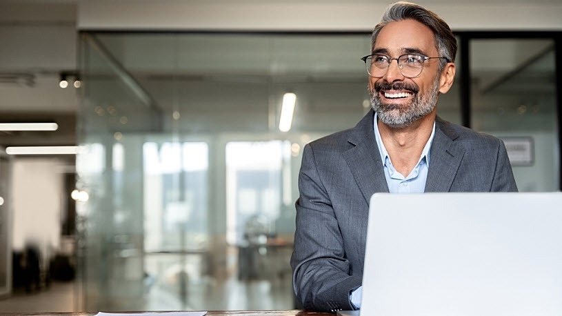 Mature businessman smiling while working at a laptop computer