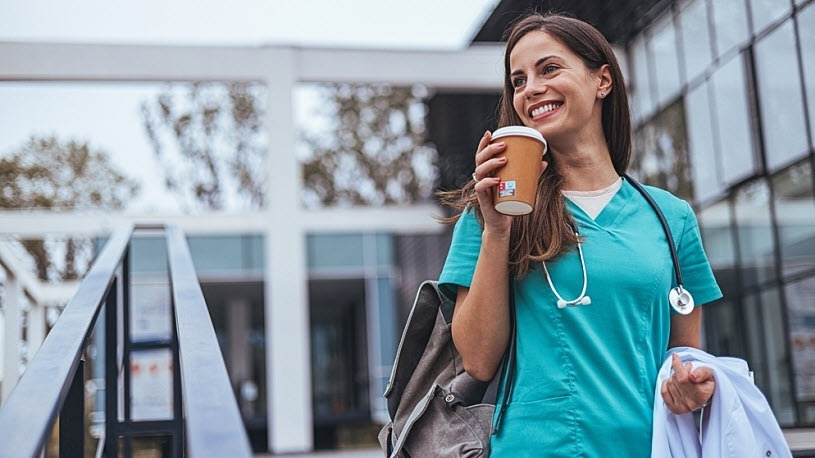 Nurse with bag in hand drinking coffee leaving hospital Nurse with bag in hand drinking coffee leaving hospital