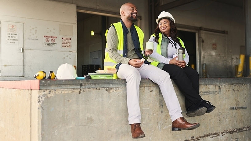 Logistics coworkers smiling during lunch break on a dock ledge
