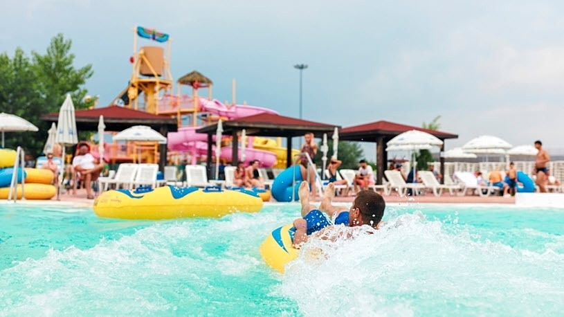 A boy floats in a yellow inner tube in the pool of a water park