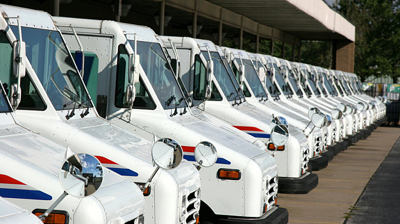 USPS delivery trucks parked in line