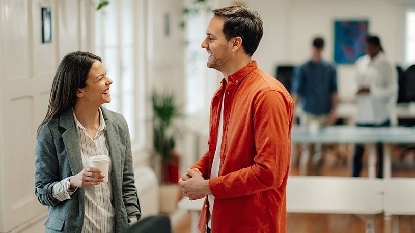 Two cheerful business colleagues are enjoying a friendly conversation during their office break