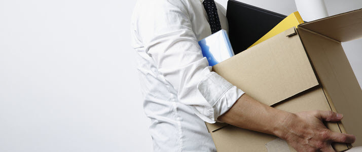 An employee gathers up office supplies in a cardboard box