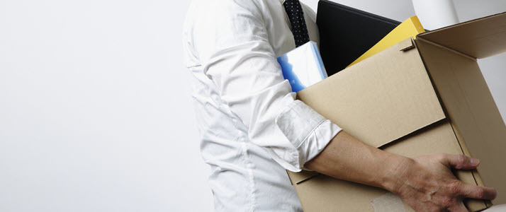 Employer Responsibility for Unemployment Benefits An employee gathers up office supplies in a cardboard box