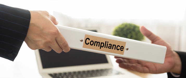 Managing Compliance Requires a Willingness to Examine Trends A person hands over a binder of compliance regulations