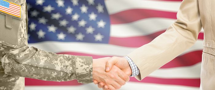 A military man&nbsp;and a business person shake hands.
