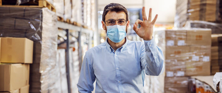 young businessman wearing mask in warehouse