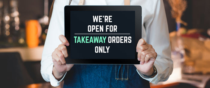 Restaurant worker holding sign promoting takeout orders only